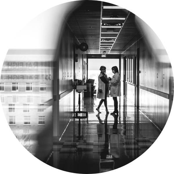 Two nurse practitioners talk in a hallway